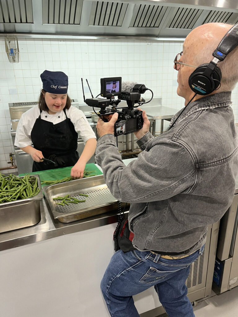 Trevor films Camille in the kitchen.